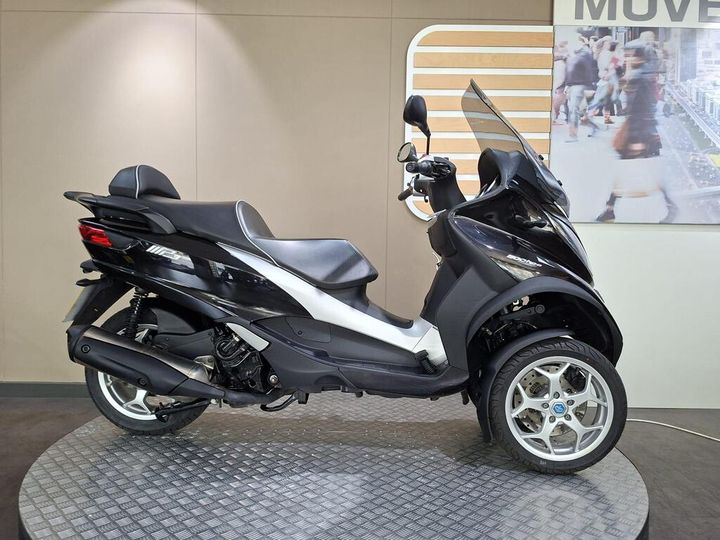 Piaggio MP3 500 Business 2021 A black and silver three-wheeled scooter displayed on a checkered platform against a neutral background.