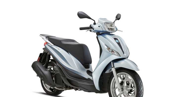 A light blue scooter with a smooth, sleek design, featuring a comfortable seat, front mirrors, and a distinctive headlight. The scooter is positioned at an angle, showcasing its wheels and stylish bodywork.